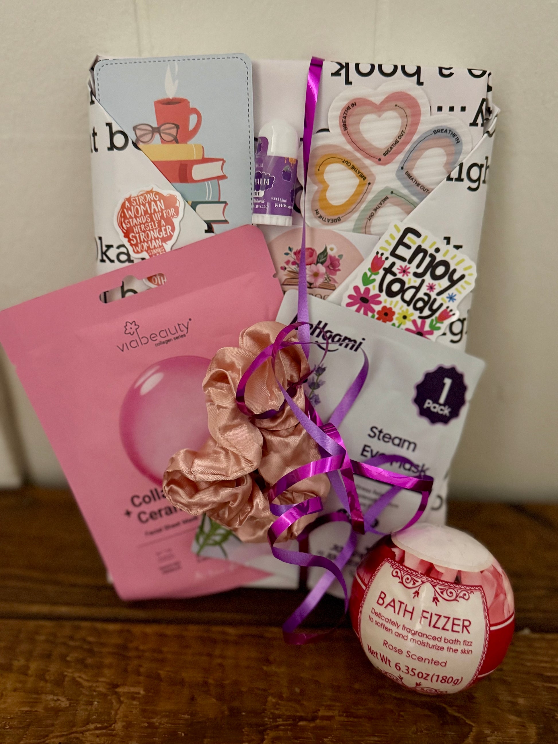 Collection of beauty products including a scrunchie, bath fizzer, and other items on a wooden surface.