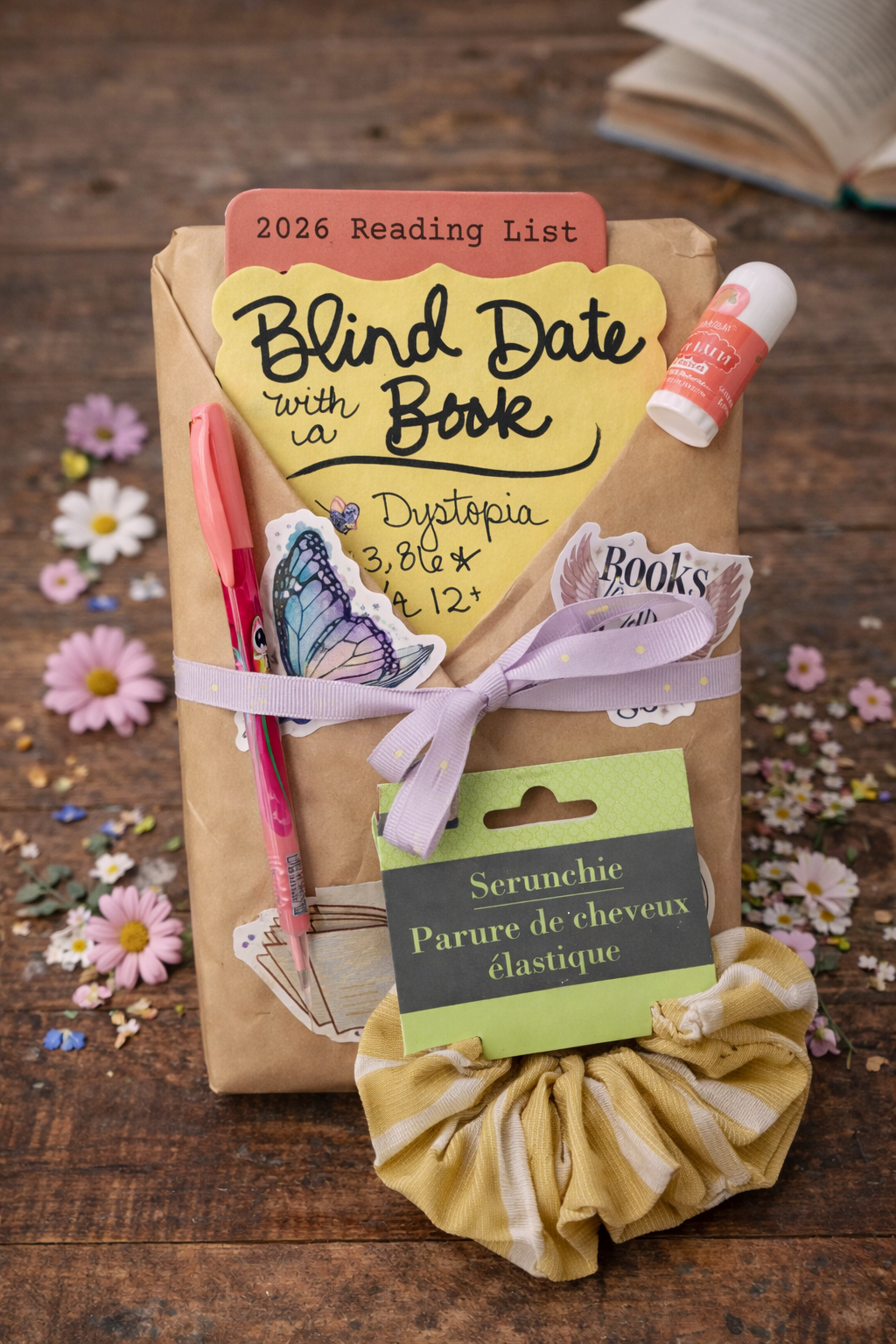 Gift set with 'Blind Date with a Book' card, pen, hair tie, and small book on a wooden surface.