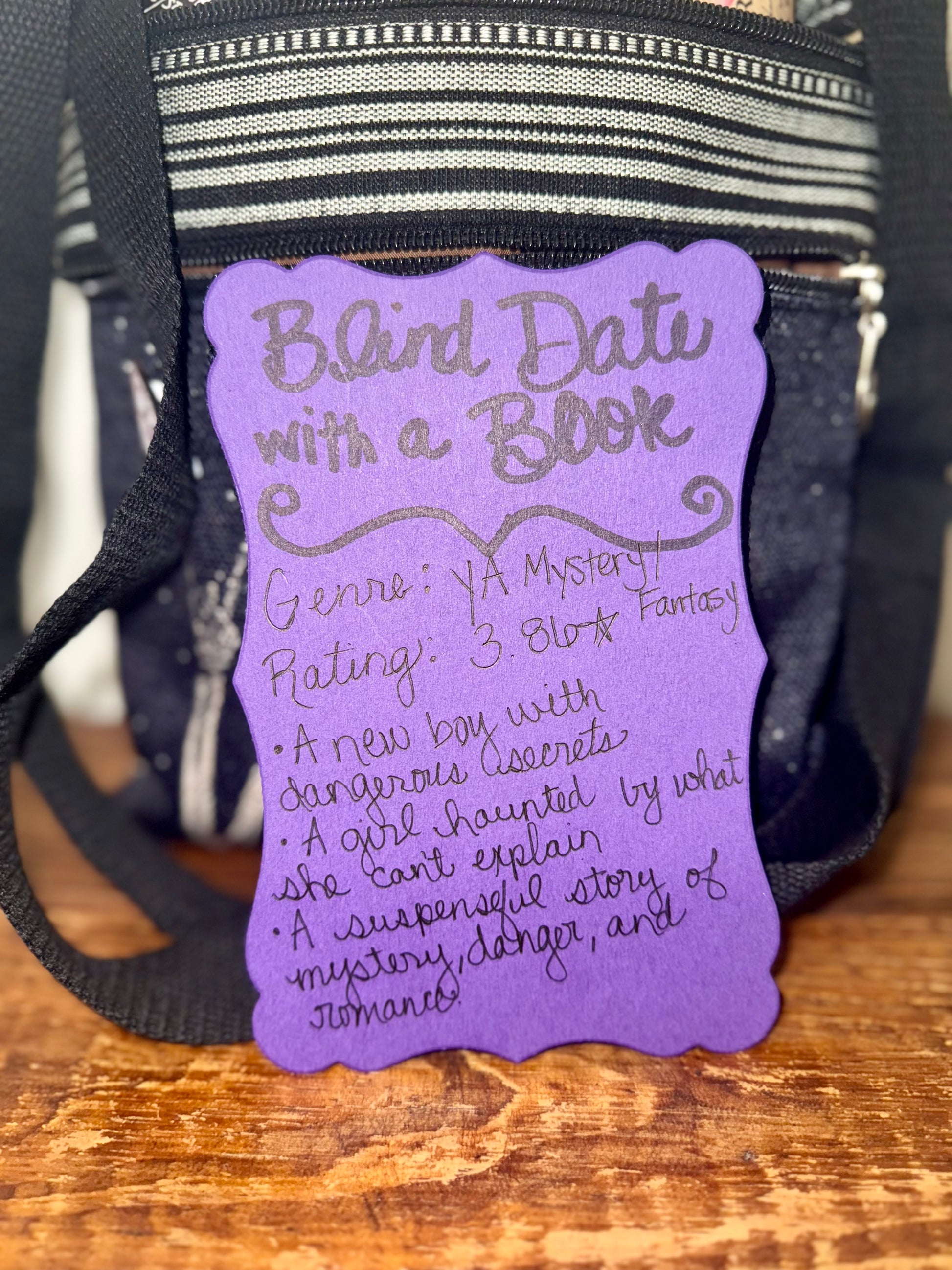 Purple book tag with text on a black bag