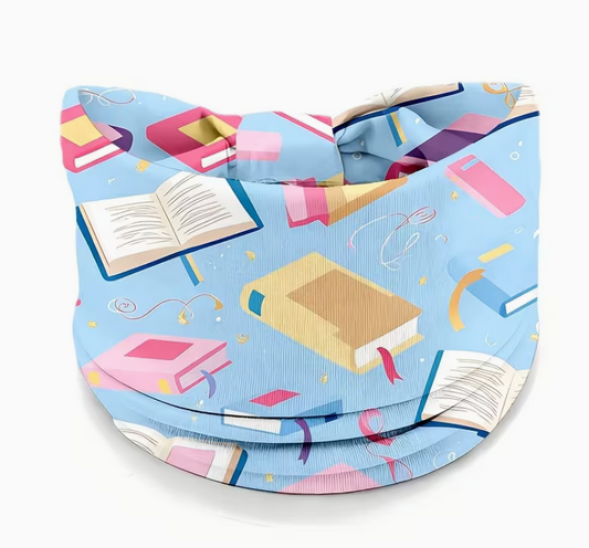 Blue twist headband featuring colorful scattered books and open book illustrations, soft stretchy fabric for reading, yoga, running, travel, and everyday wear.