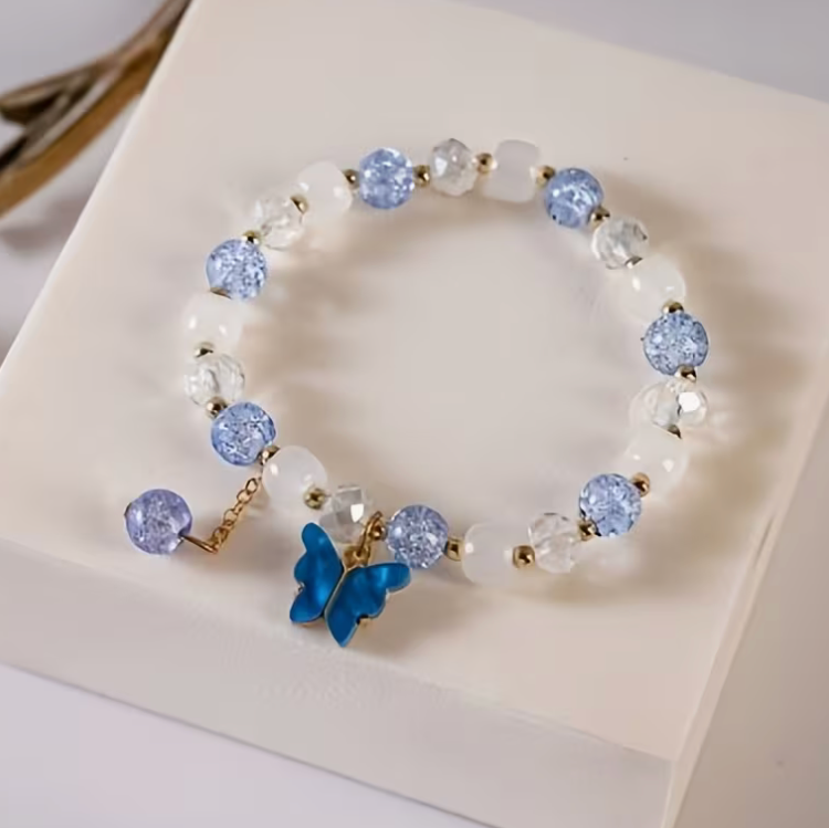 Blue and white beaded bracelet with clear faceted beads gold tone accents and blue butterfly charm