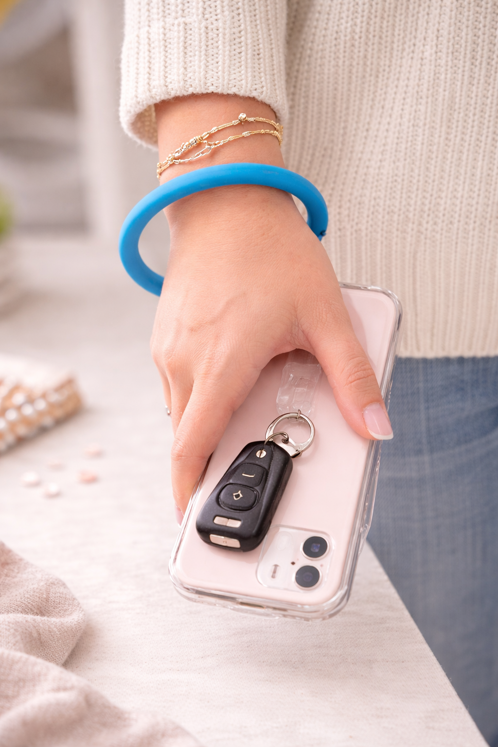 Person wearing blue wristlet bracelet while holding phone and keys