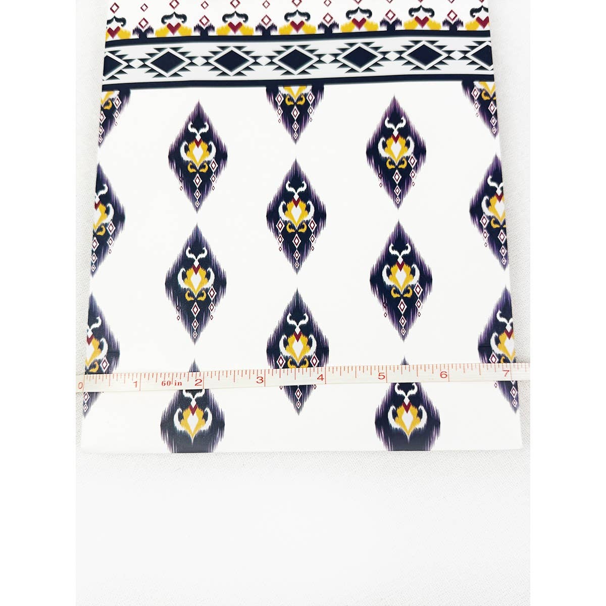 Decorative fabric with a pattern and a ruler for scale on a white background