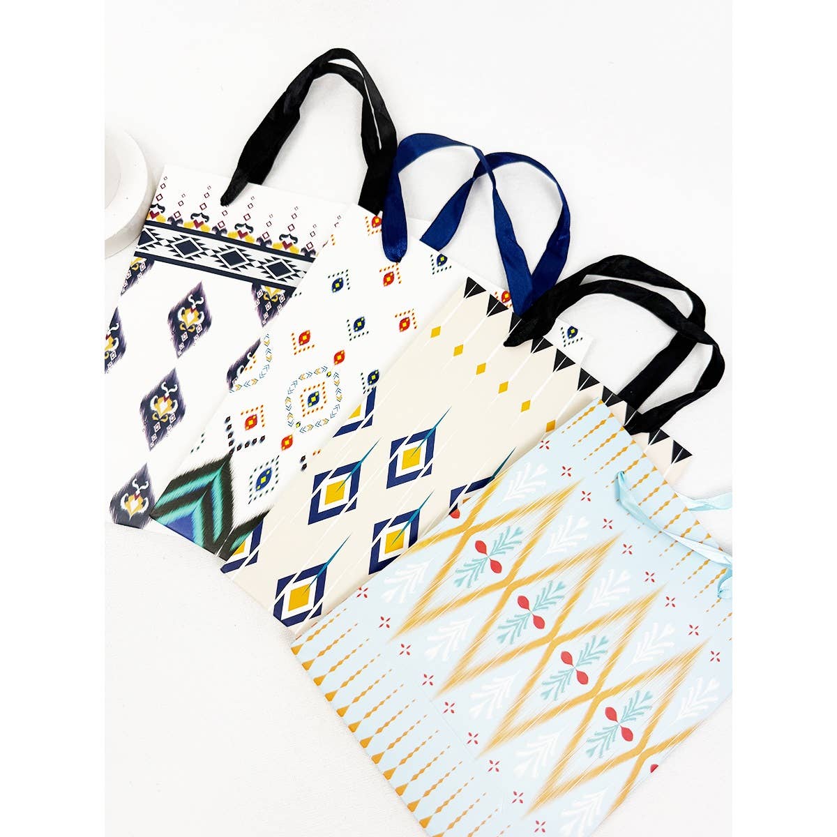 Assorted boho-style medium gift bags with geometric patterns and handles displayed together with size reference and individual designs