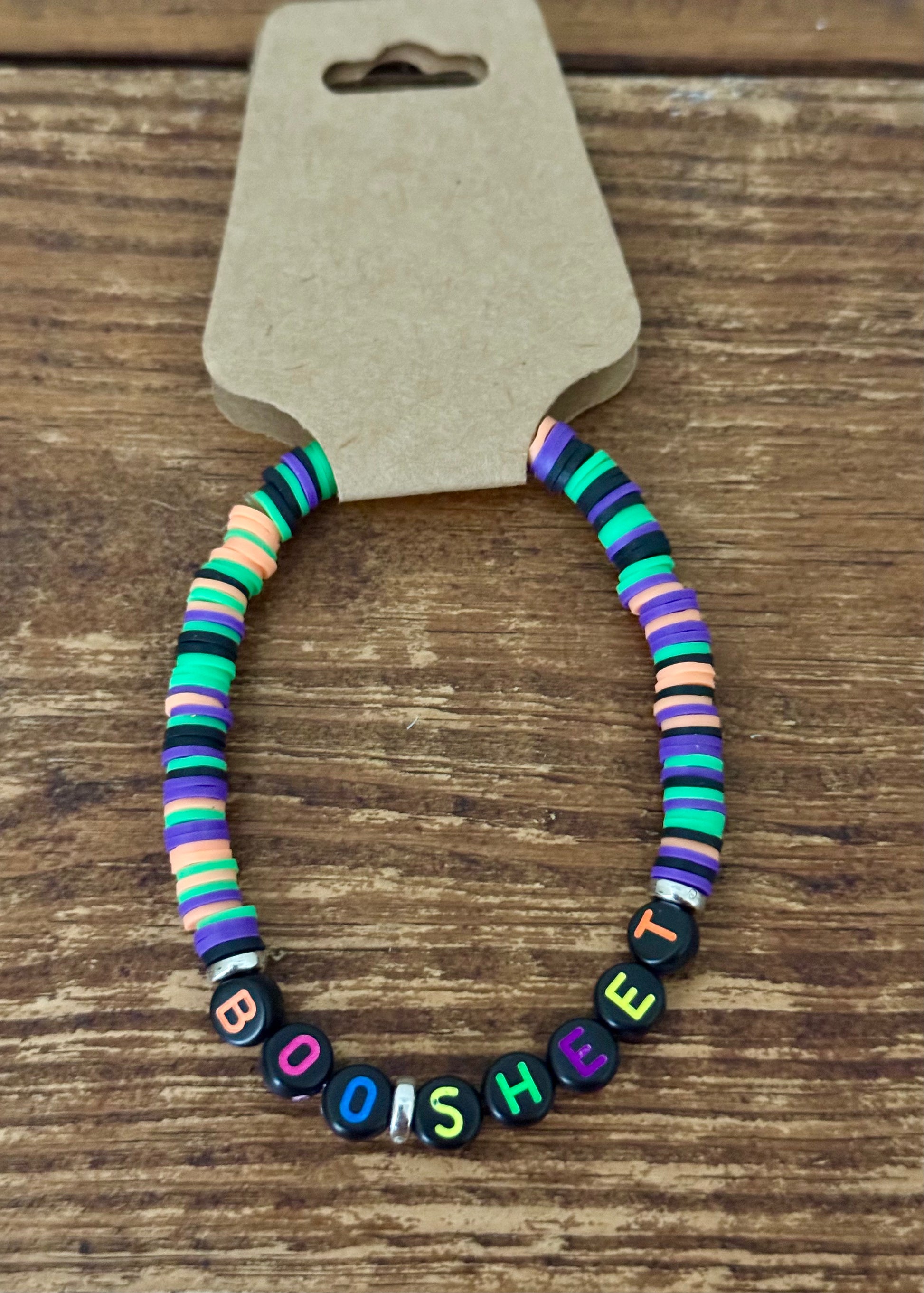 Colorful beaded bracelet with 'BOO SHEET' charm on a wooden surface