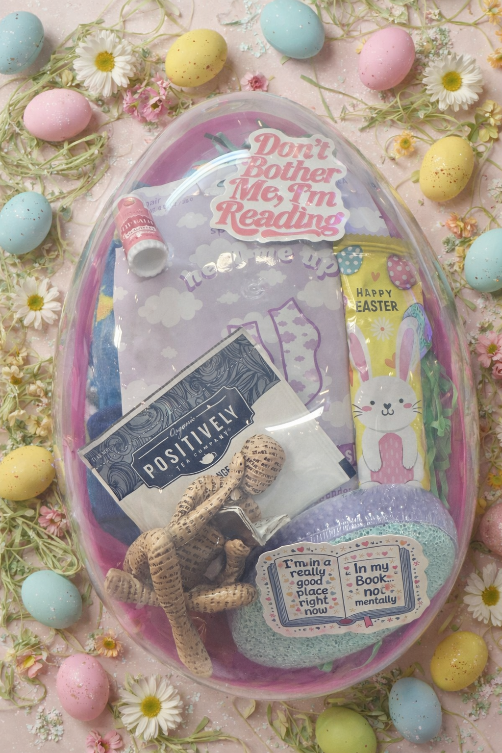 Clear reusable Easter egg filled with bookish and pampering self care products styled with pastel eggs and spring flowers.