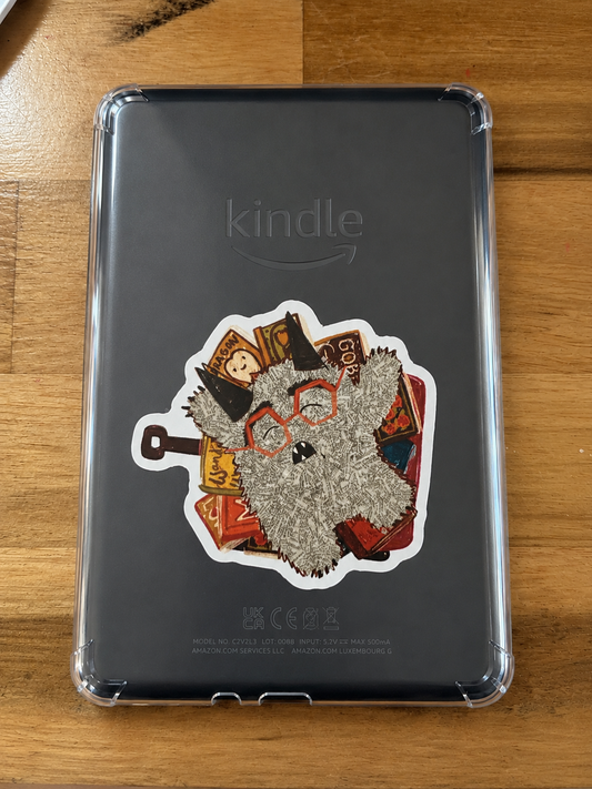 Cute fuzzy Book Monster character surrounded by books displayed as a vinyl sticker on the back of a Kindle inside a clear case.