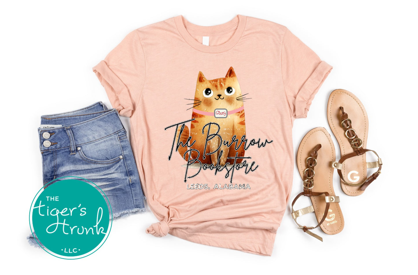 The Burrow Bookstore cat shirt with illustrated orange cat design on a soft peach tee