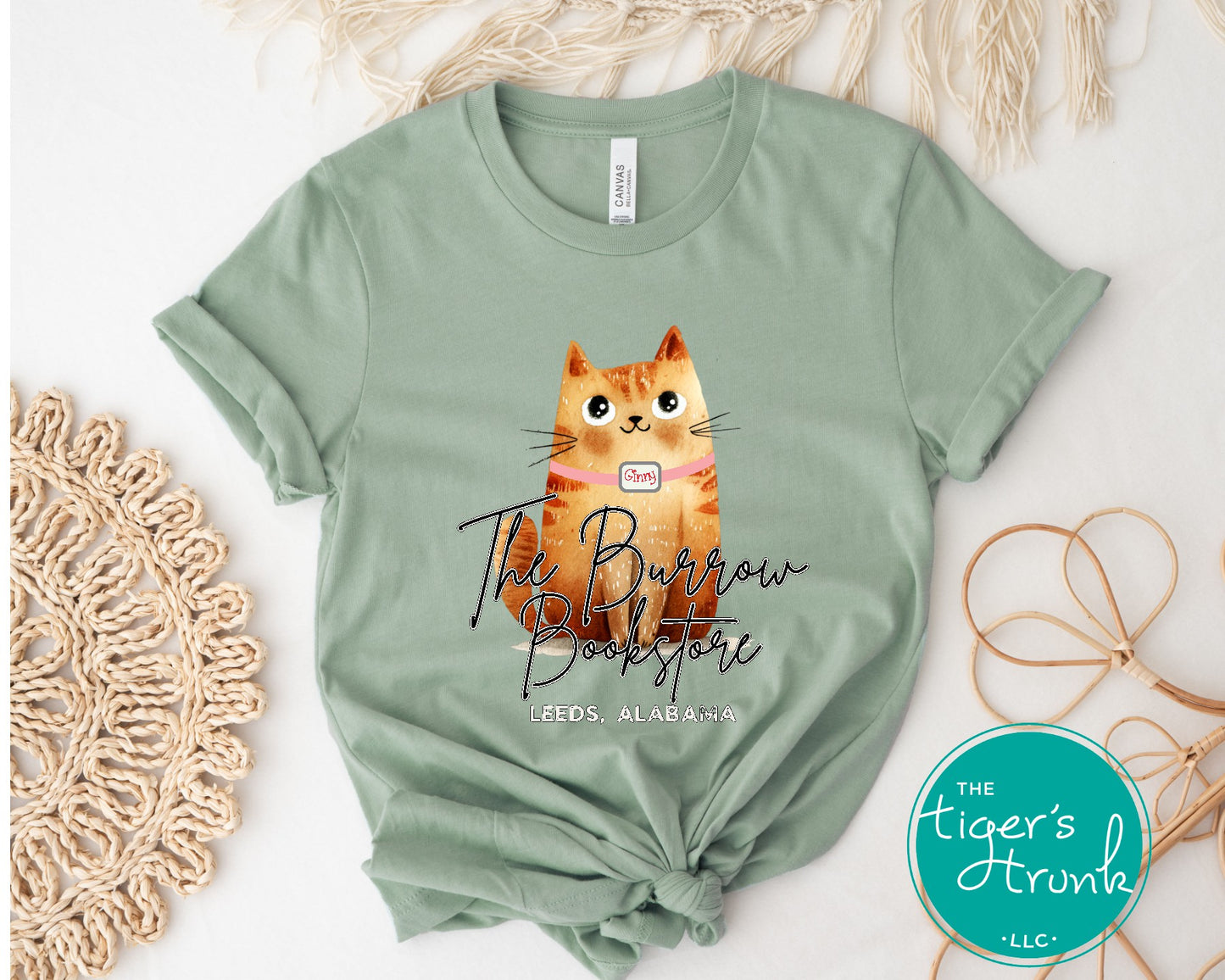 The Burrow Bookstore cat shirt with illustrated orange cat design on a soft sage shirt