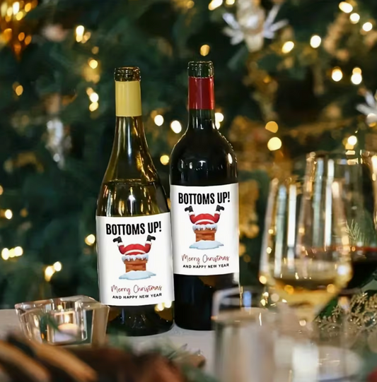Festive Christmas wine bottle label with glittery upside down design featuring Christmas boots and snowflakes, displayed on a holiday themed background