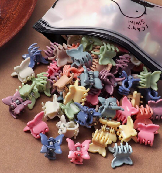 Assorted colorful hair clips on a brown surface with a pink pouch labeled 'Cant Swim' in the background.