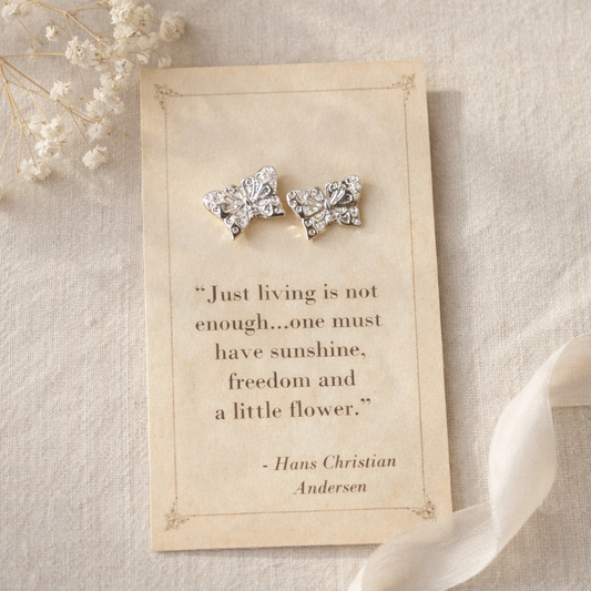 Silver butterfly stud earrings displayed on a vintage style quote card with soft neutral background and delicate floral accents