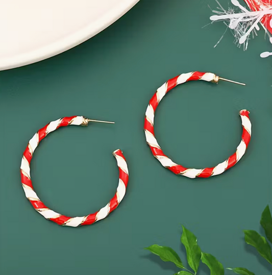 Red and white holiday hoop earrings displayed on green background.