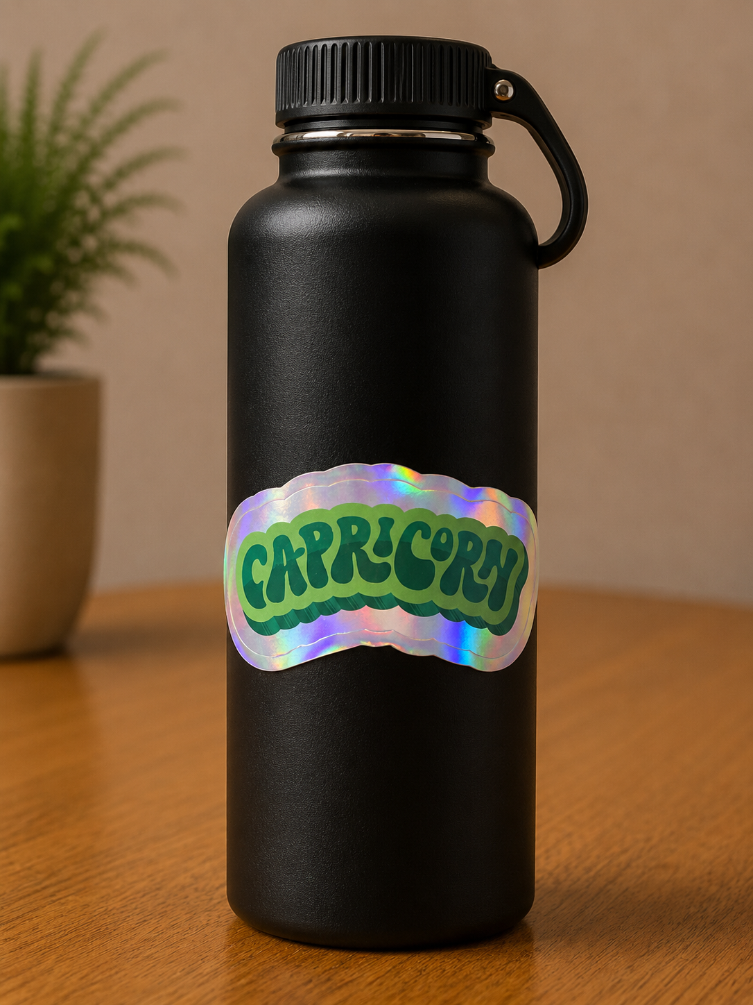 Capricorn holographic zodiac vinyl sticker on a black insulated water bottle featuring bold retro lettering.