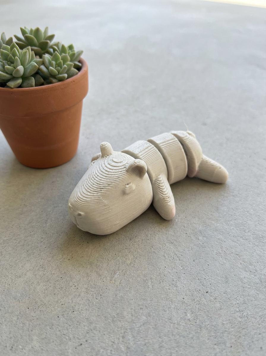 3d printed hippo toy on a light surface next to a potted plant