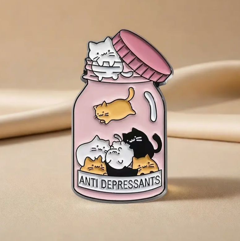 Cat Antidepressants enamel pin featuring a pink jar filled with cats and the words Antidepressants, cute and comforting accessory for cat lovers