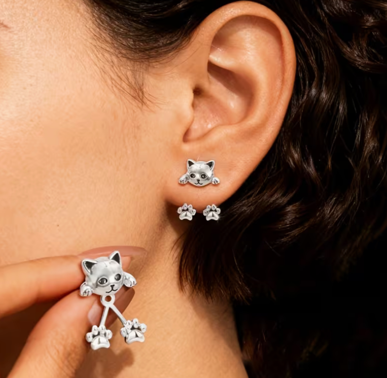Woman wearing cat back drop earrings with dangling paw design and silver tone finish