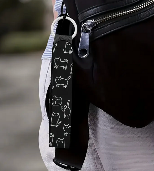 Black strap with white cat illustrations on a black bag.