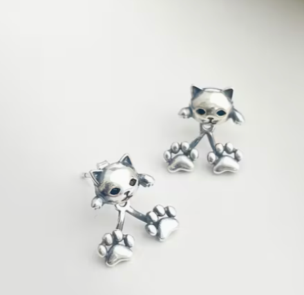 Silver cat earrings with dangling paw details displayed on neutral background