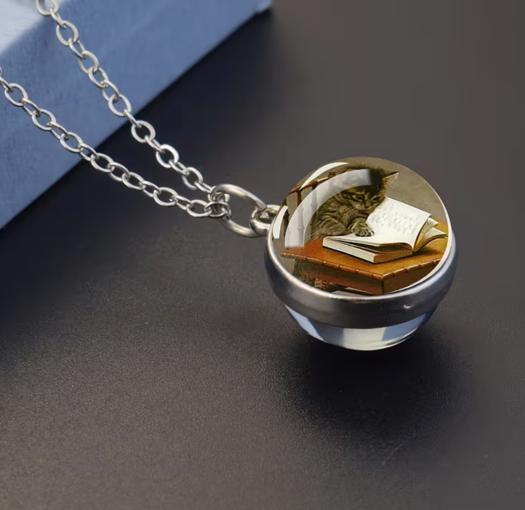Cat reading an open book glass ball pendant necklace with silver-tone chain.