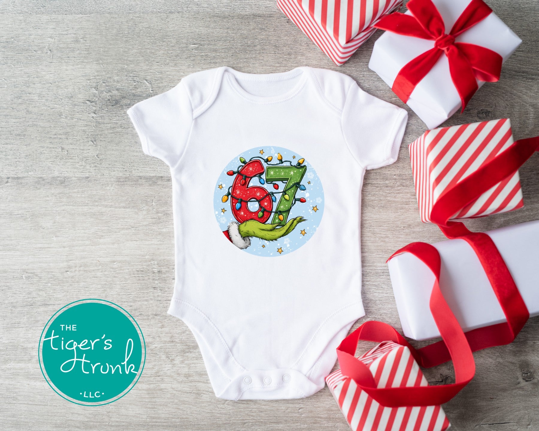 White 18-month Christmas baby bodysuit featuring a festive 67 design with Christmas lights and a Grinch-inspired hand.