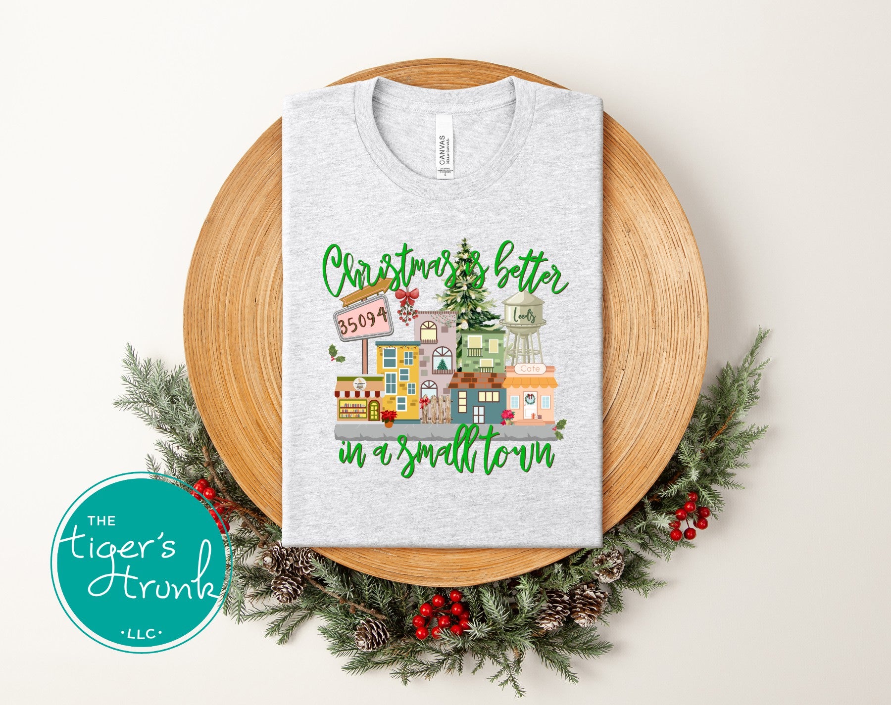 Heather ash Christmas shirt with small-town holiday village design and festive lettering.
