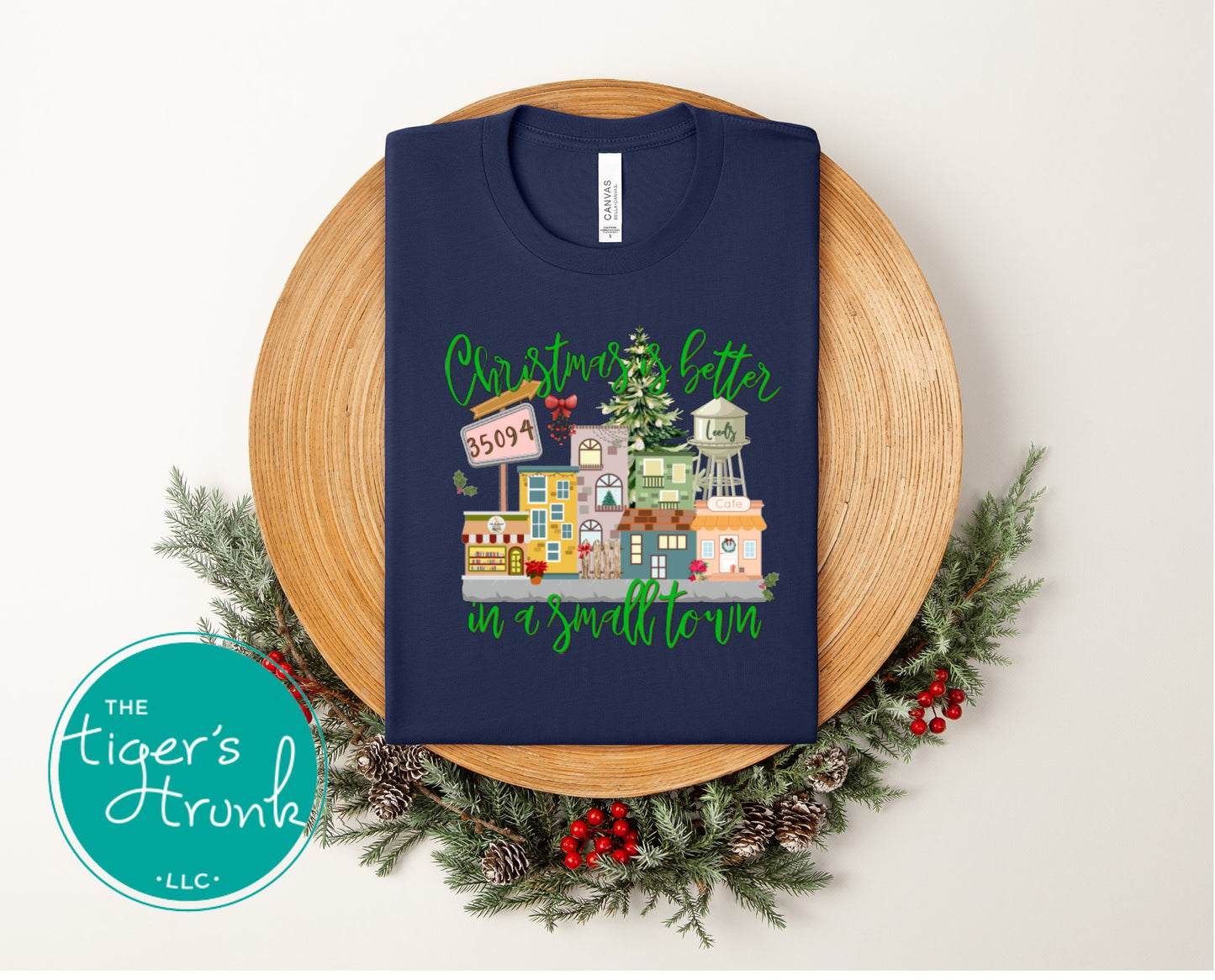 Navy blue Christmas shirt featuring small-town Christmas buildings, trees, and festive text.