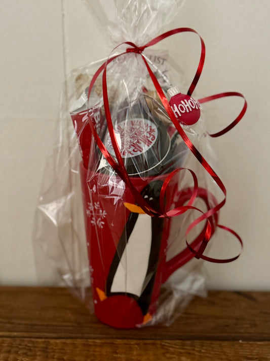 Red mug with a white design, wrapped in clear cellophane with red ribbons, on a wooden surface.