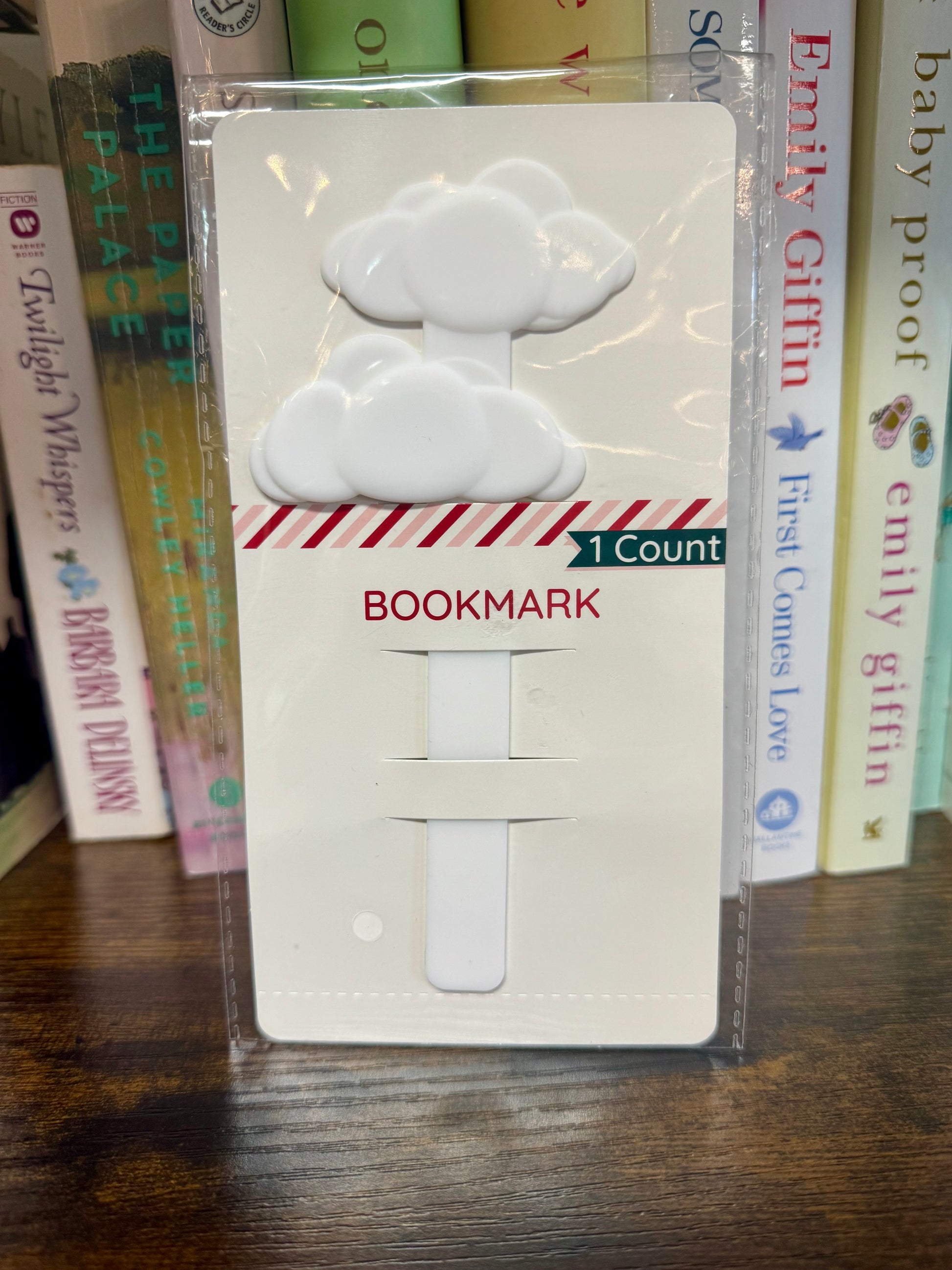 White cloud-shaped bookmark in packaging with books in the background