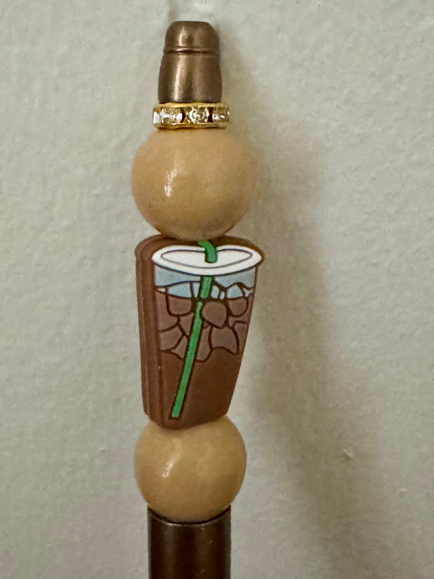 Decorative bottle stopper with a design of a coffee cup and straw on a plain background
