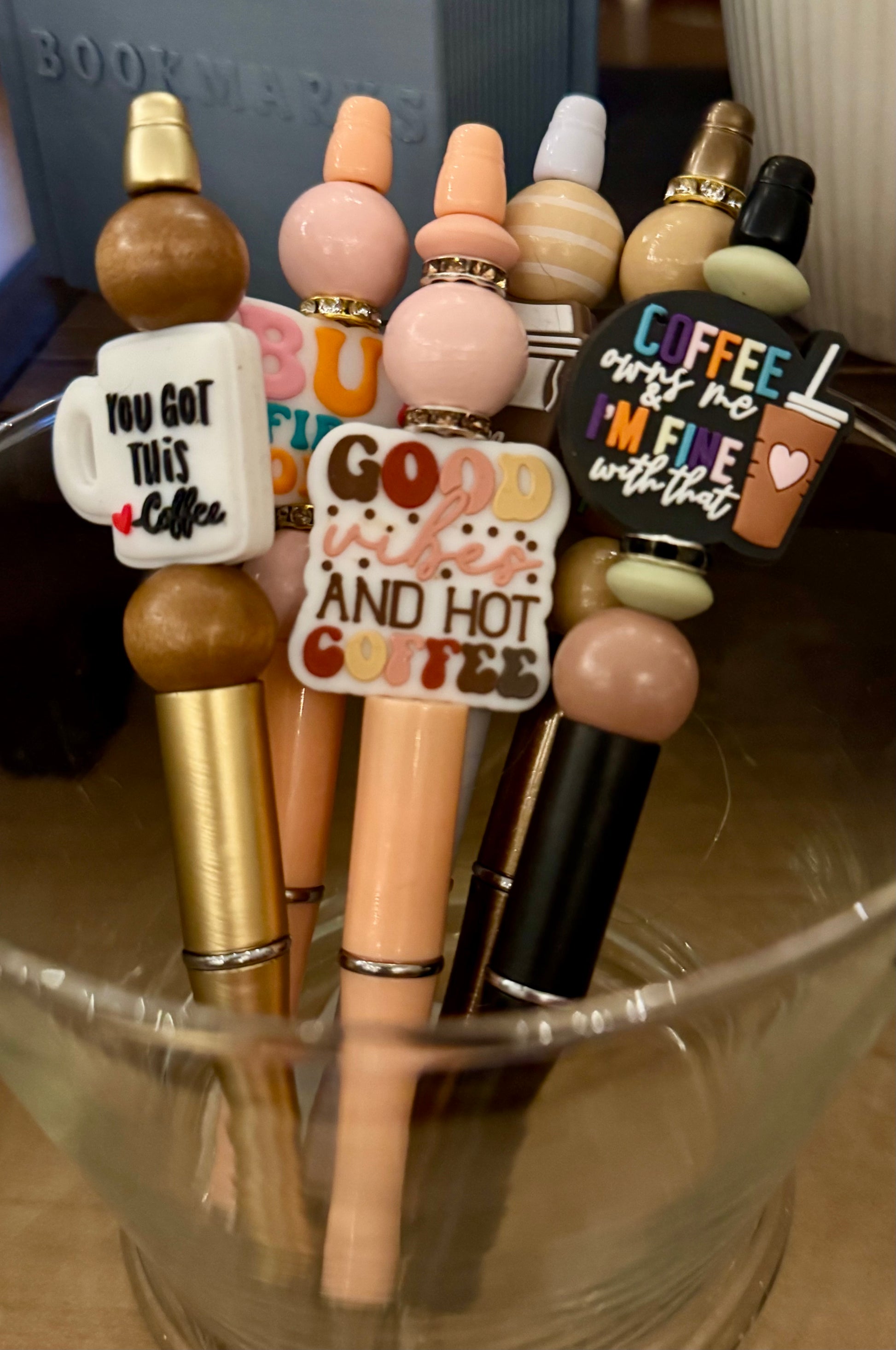 Decorative pens with various designs and text in a glass container
