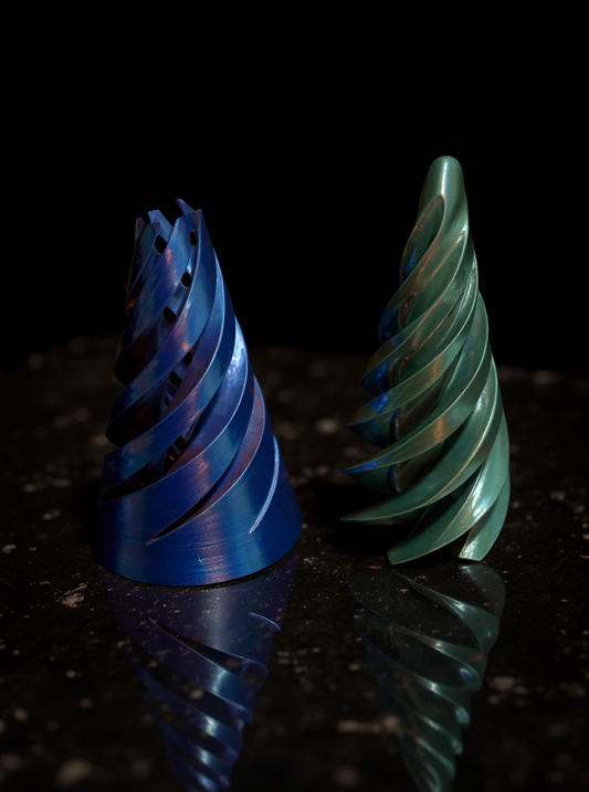 Blue and green metallic 3D printed cone fidget puzzles displayed on a dark reflective surface.