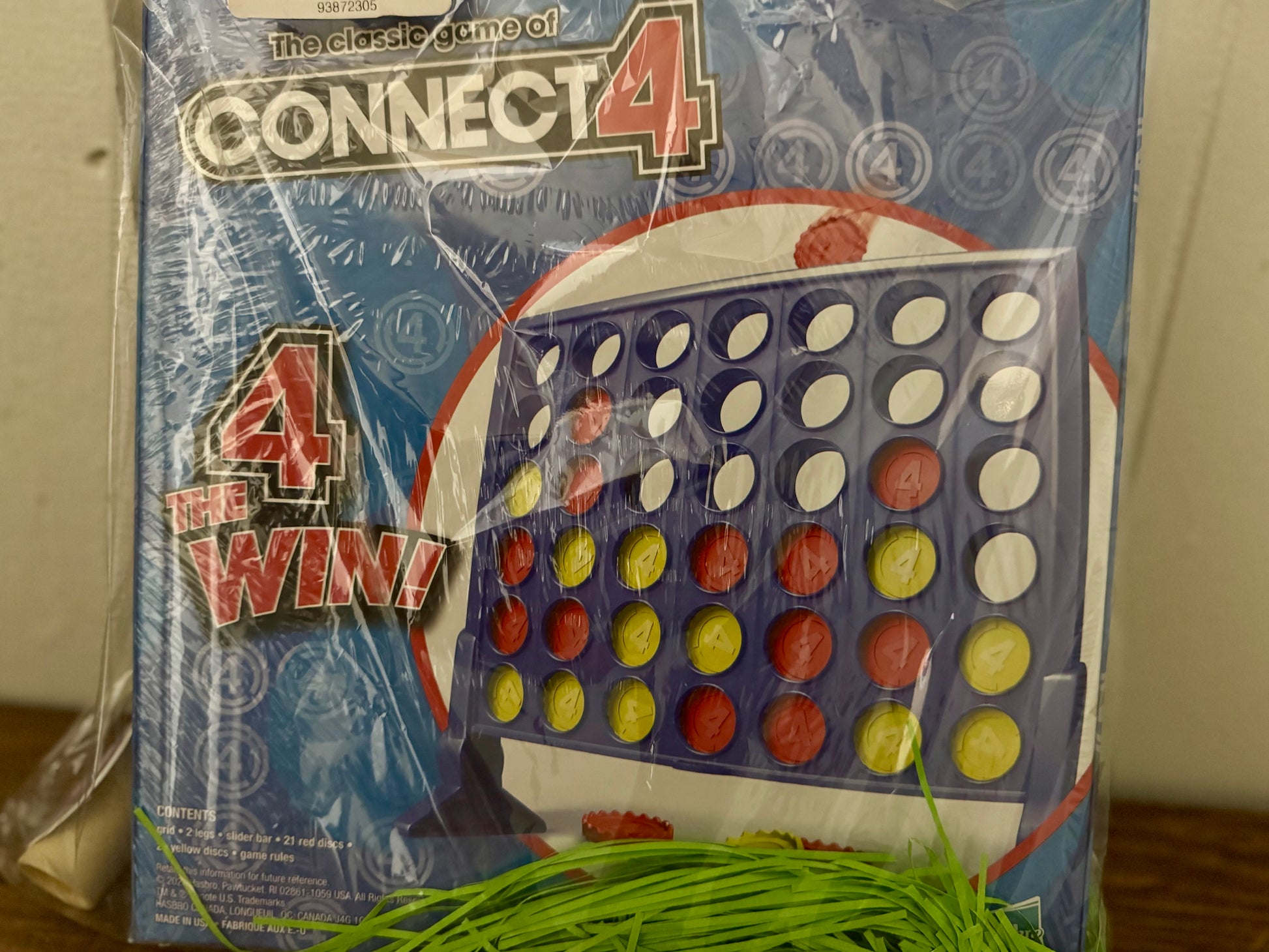 Connect 4 board game box wrapped inside the kids gift bag with green paper grass at the bottom.