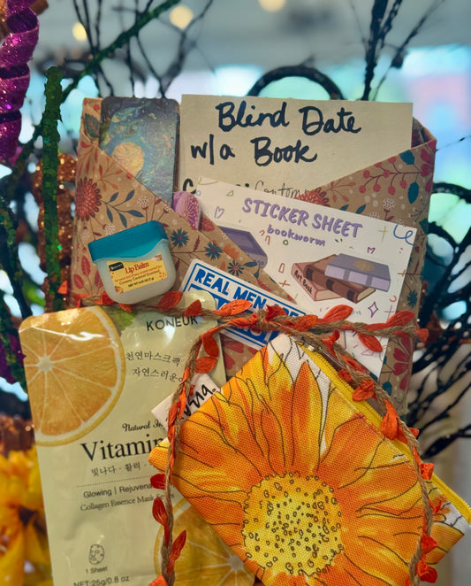 Gift basket with various items including a sunflower-themed product, vitamin package, and stationery items.