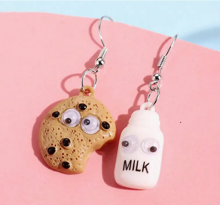 Cookie and milk bottle earrings on a pink and blue background