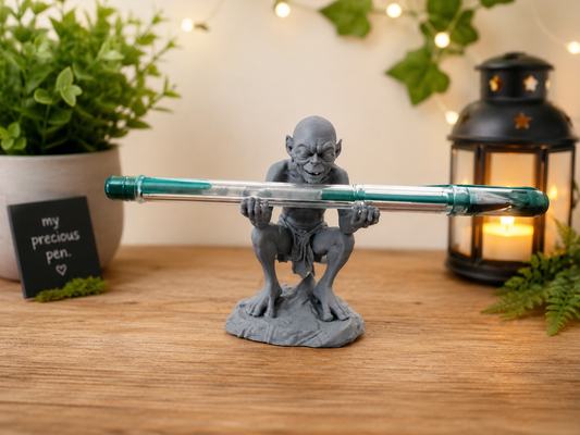 Fantasy-inspired creature pen holder displaying a green pen on a wooden desk with cozy decor