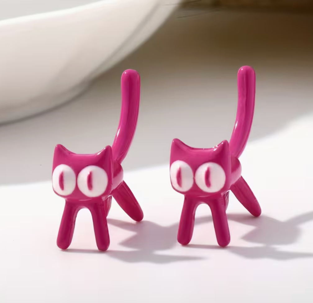 Pink cartoon cat stud earrings with oversized eyes and curled tails