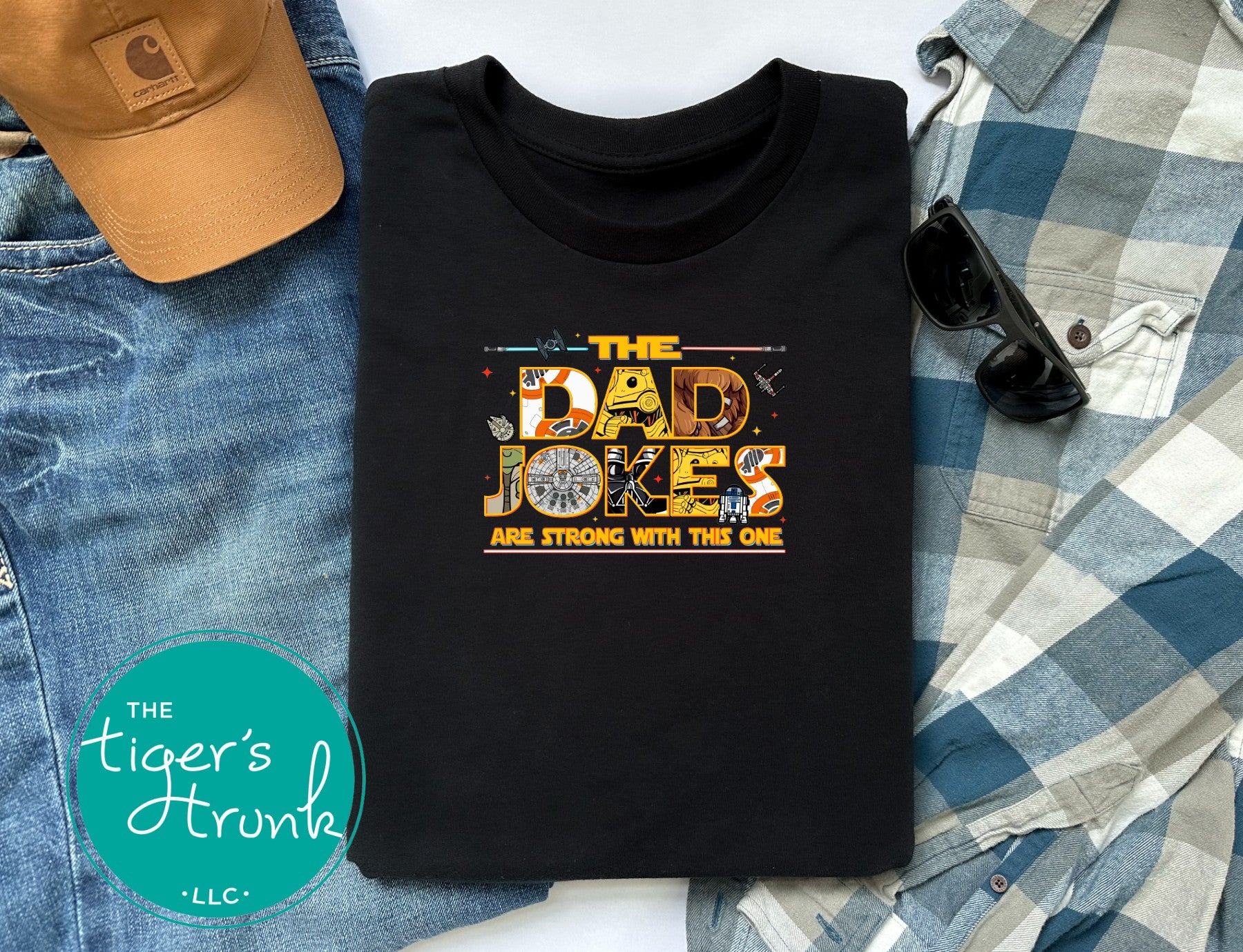 Black graphic t-shirt with funny dad jokes inspired space-themed design styled with jeans, flannel shirt, sunglasses, and hat