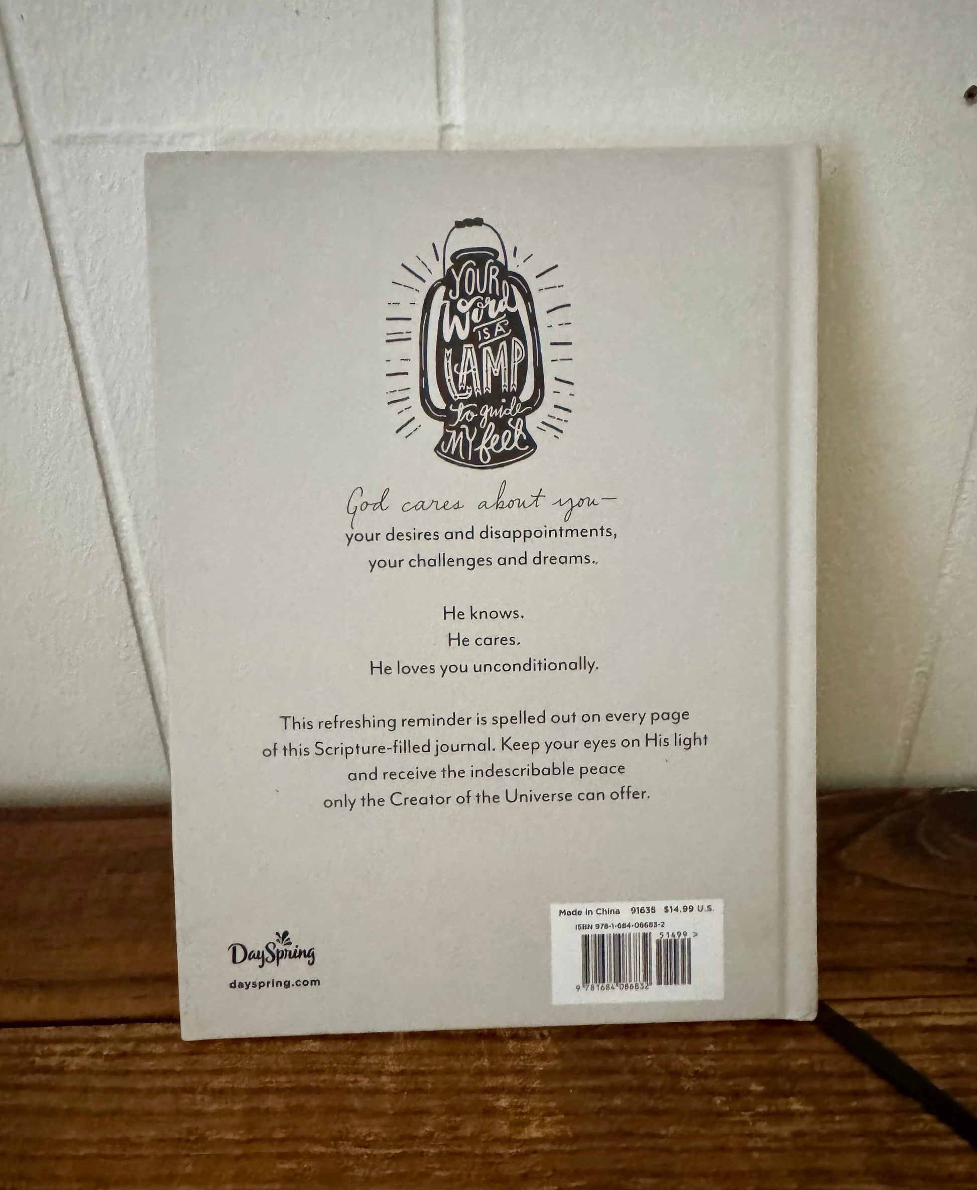 Back cover of a book with text and a logo on a wooden surface.