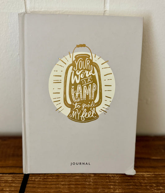 Journal with a decorative cover featuring text and a lamp illustration on a wooden surface.
