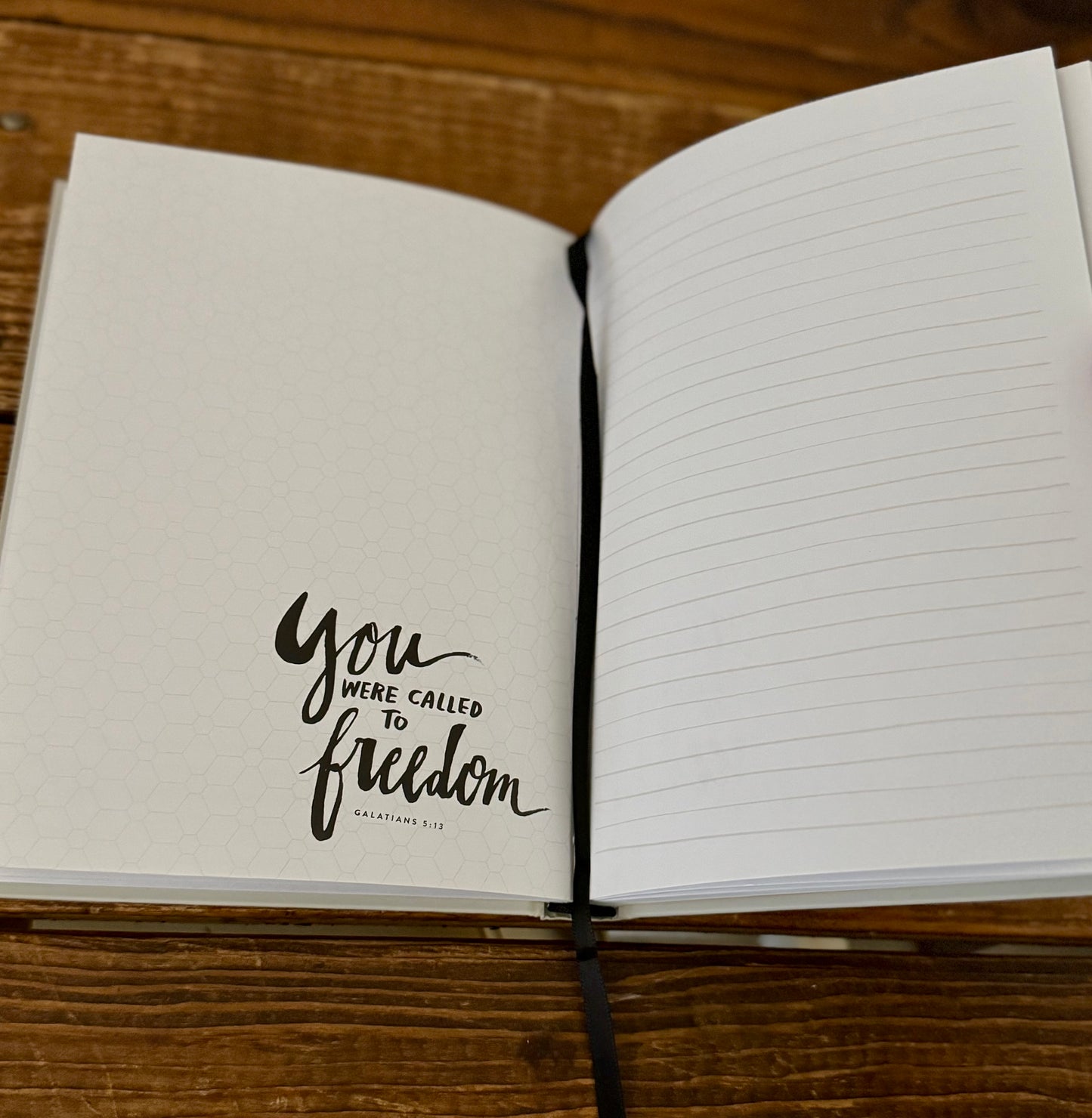 Open notebook with 'You were called to freedom' text on a wooden surface