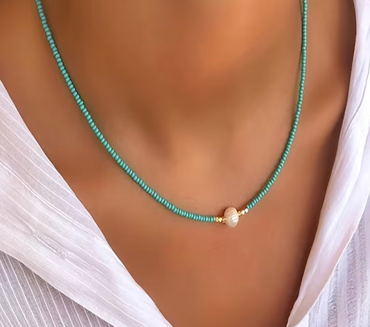 Turquoise beaded necklace with a pearl pendant on a mannequin wearing a white top.