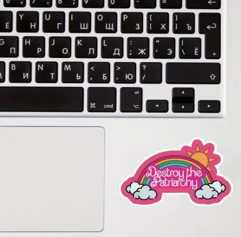 Colorful Destroy the Patriarchy rainbow sticker displayed on a laptop beside a keyboard and trackpad