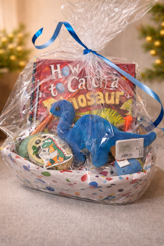 Dinosaur-themed kids gift basket with plush blue dinosaur, dinosaur book, and themed items wrapped in clear gift wrap with blue ribbon