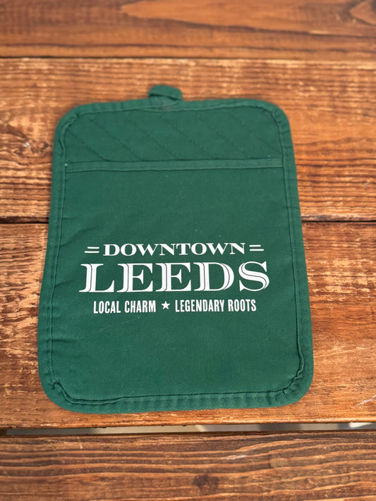 Green pot holder with 'Downtown Leeds' text on a wooden surface