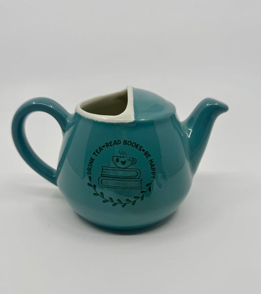 Teal ceramic teapot with text and graphics on a white background