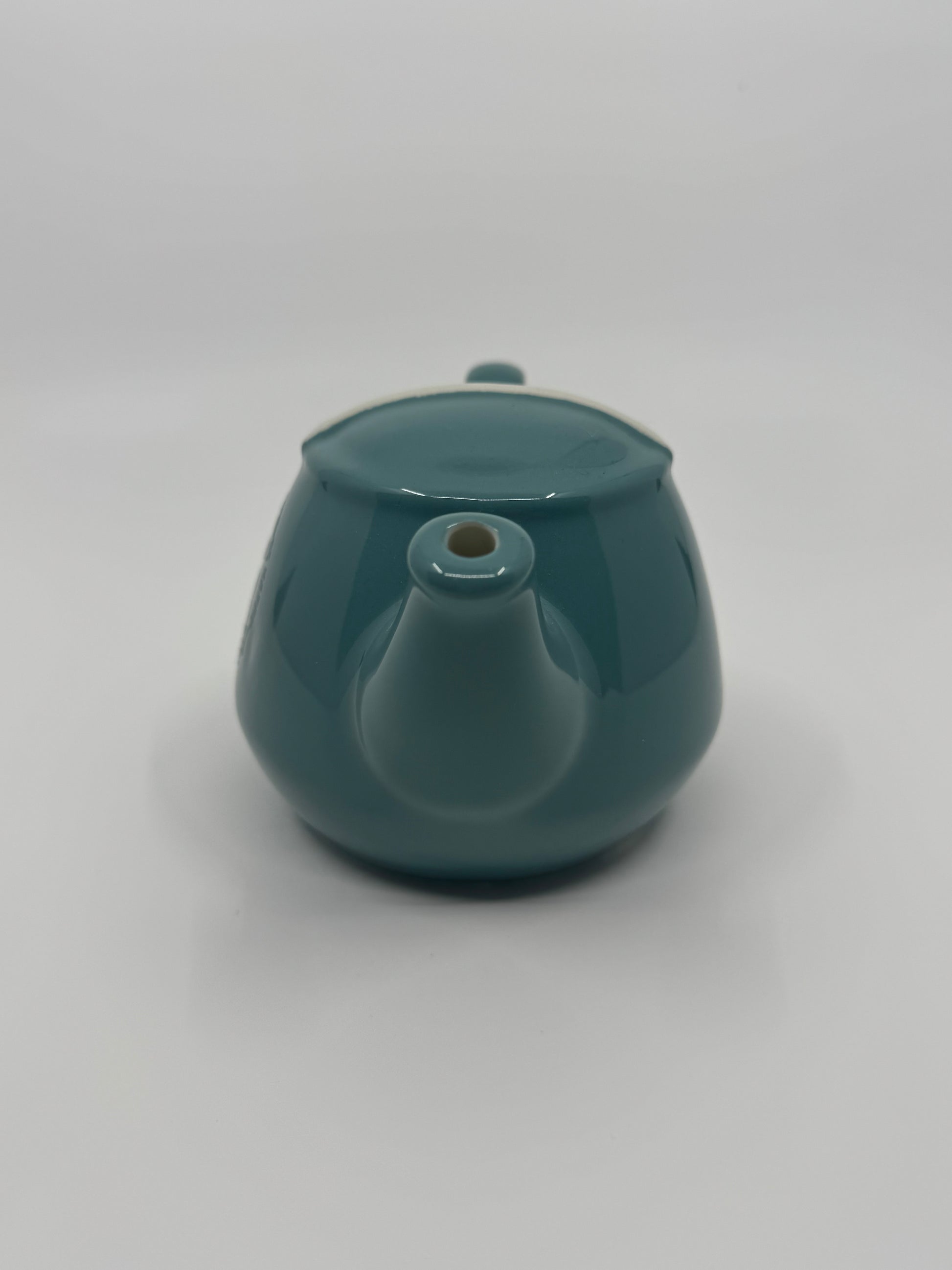 Teal ceramic teapot on a white background