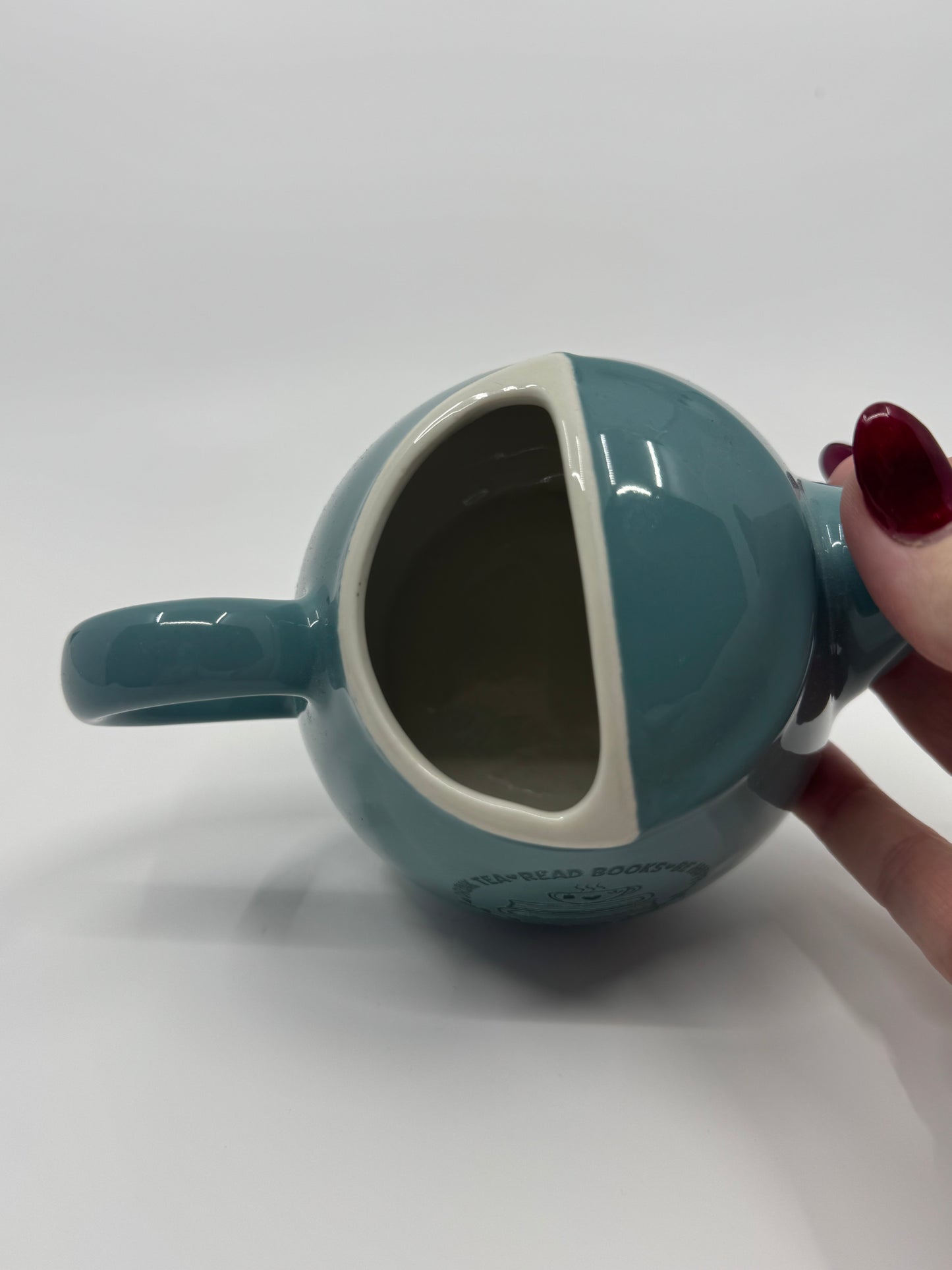 Teal mug with a handle held by a hand on a white background