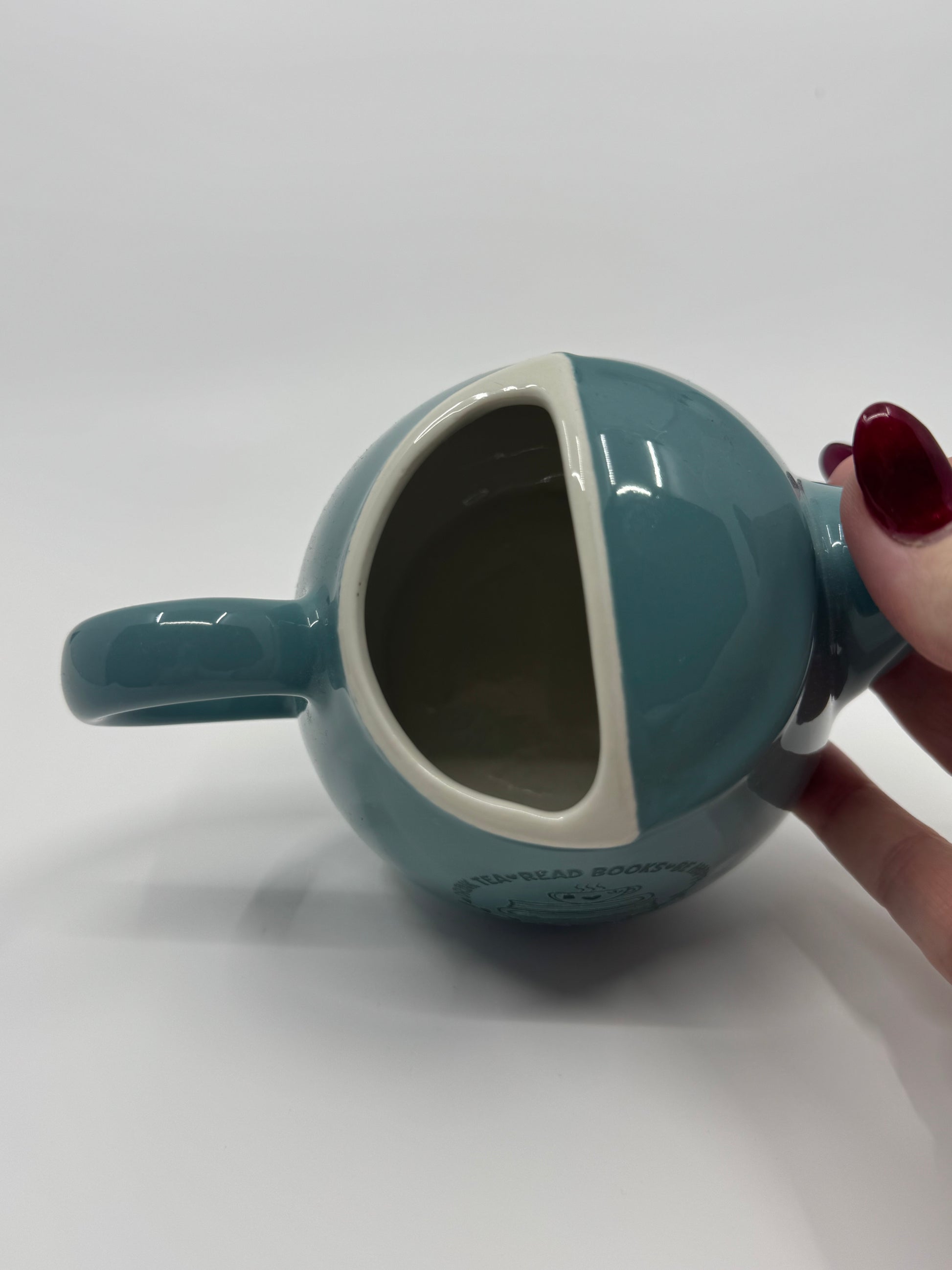 Teal mug with a handle held by a hand on a white background