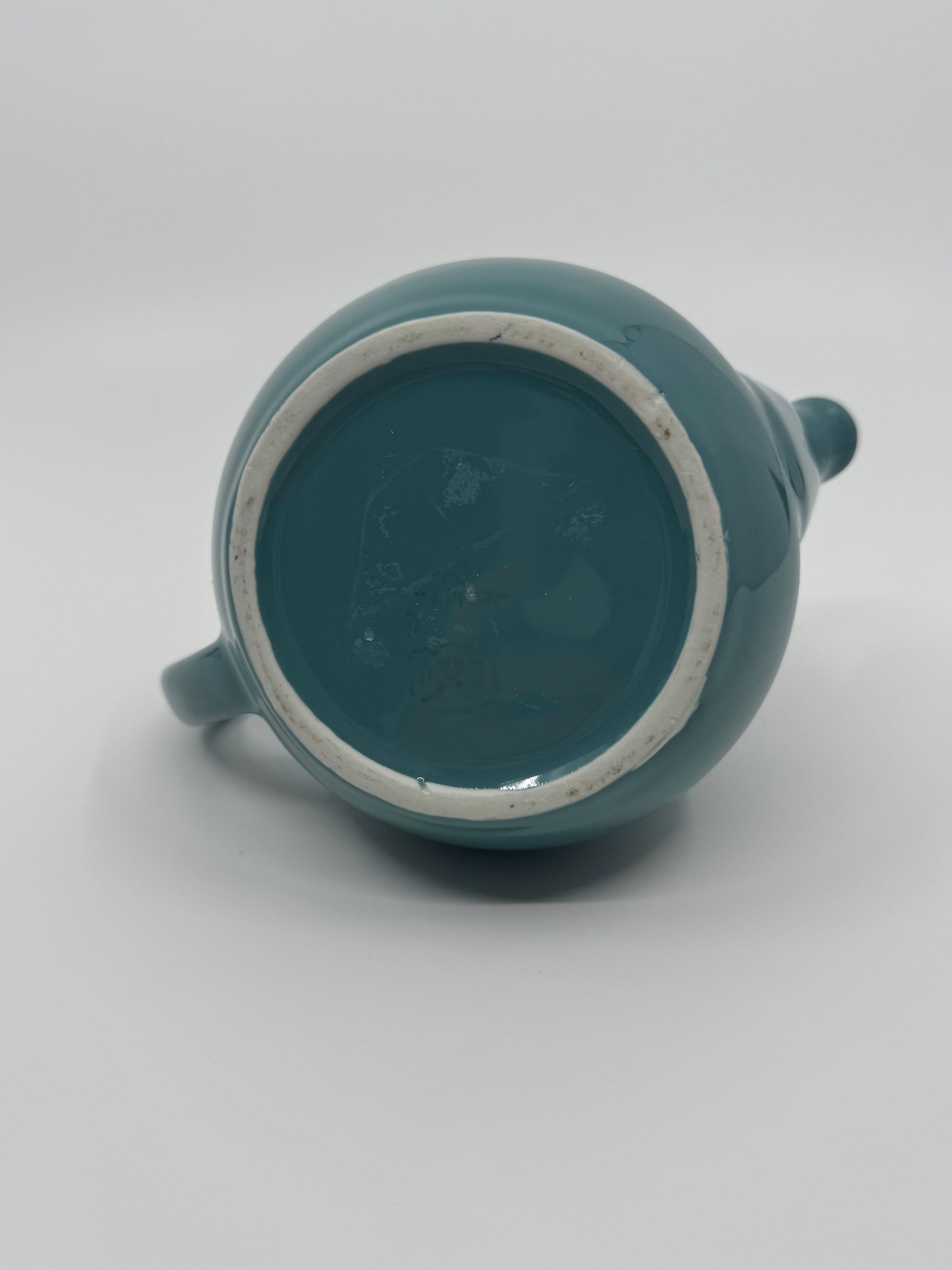 Teal ceramic teapot on a light gray background
